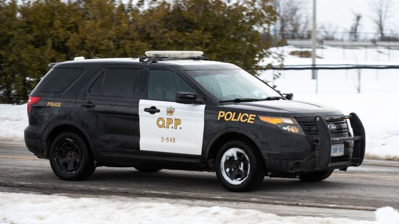 A OPP Ford-SUV drives down a road. It is snowy but the car and road are clear. 