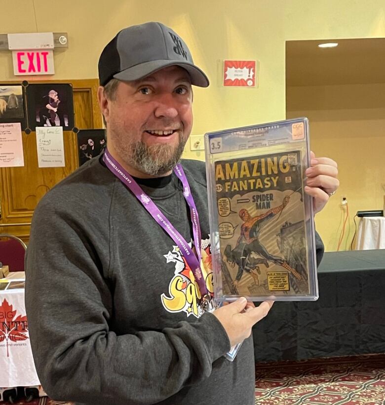 A man smiles while holding a graded copy of Amazing Fantasy #15.