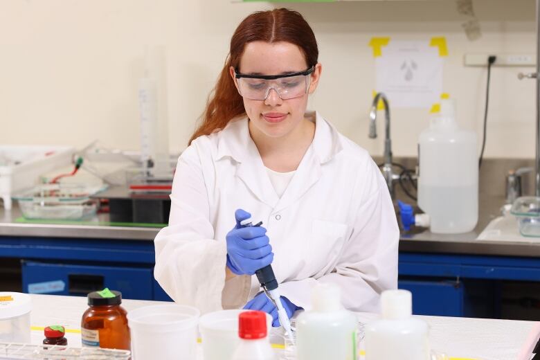 A young woman with long red hair works in a labratory.