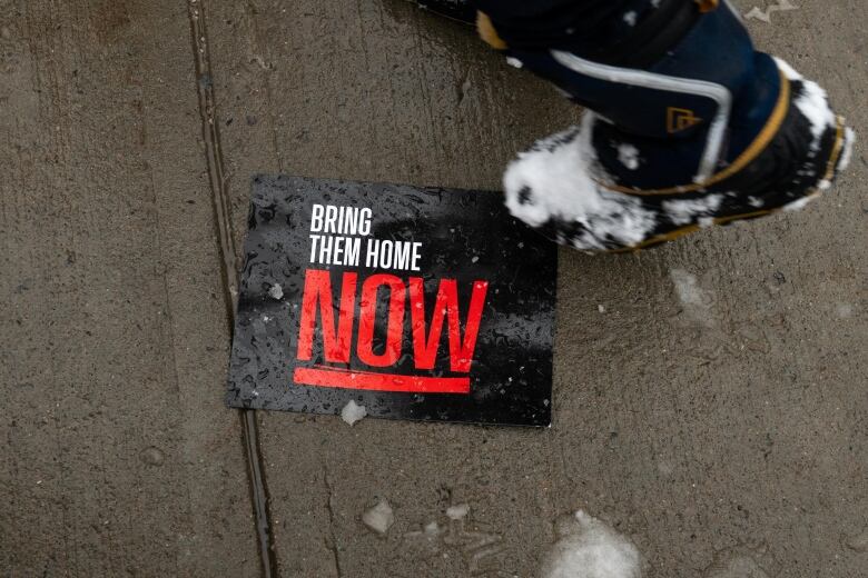 A person walks past a sign on the ground reading 'Bring them Home Now' during a pro-Israel protest on Parliament Hill in Ottawa, on Monday, Dec. 4, 2023.