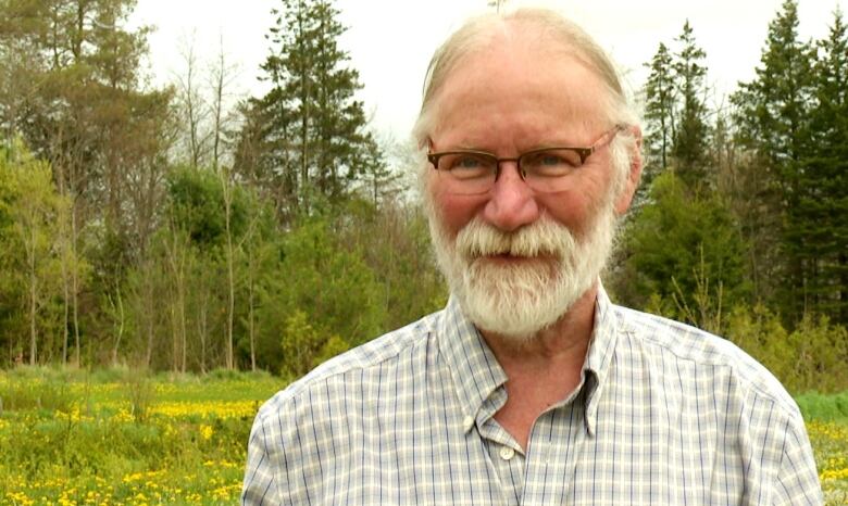 Man with grey hair standing in field.