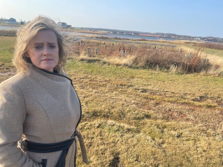 A woman looks sad with the remains of her home behind her