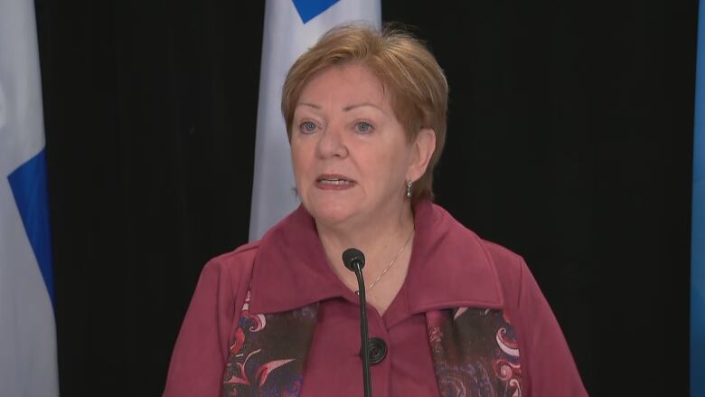 woman with short hair and pink shirt speaks into mic 