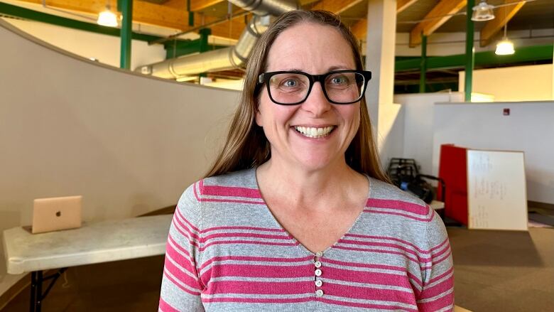 A smiling woman stands inside a large room.