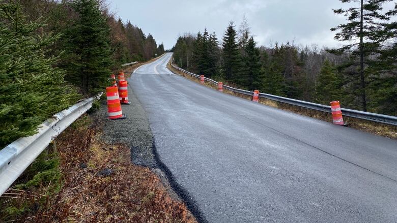 A recently paved road with pylons on the should of the road. 