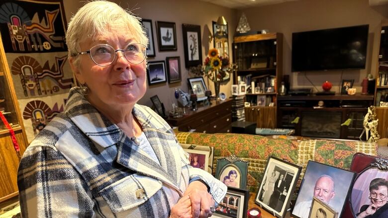 A woman standing in her home surrounded by family photos.