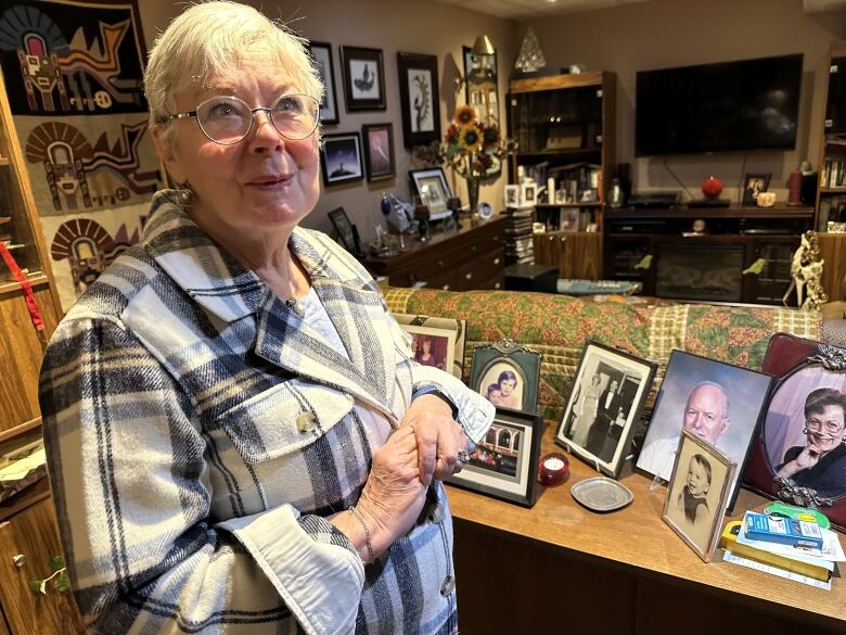 A woman standing in her home surrounded by family photos.