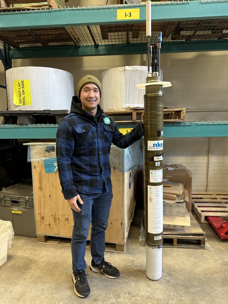 A man in black and dark blue checked shirts with a tall cylindrical machinery