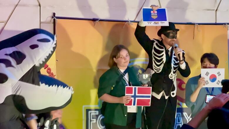 An Alberta flag is held up by someone in a skeleton suit.