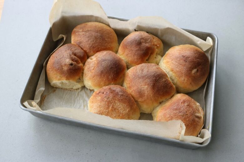 Eight buns sit on a pan. 