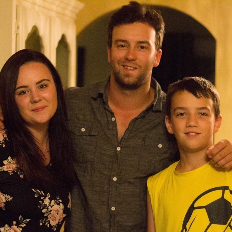 A woman, a man, and a male child stand together staring at the camera. 