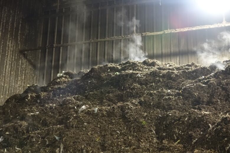 A photograph of food composting, with steam seen rising from the brown pile.