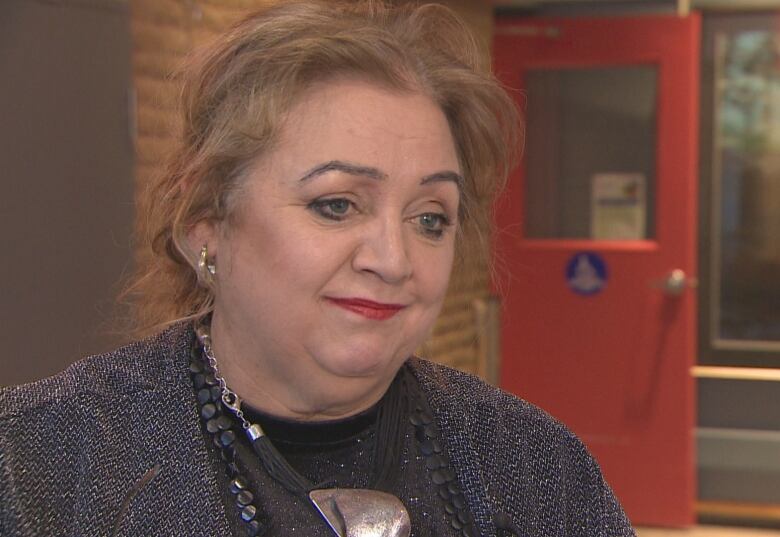 A smiling woman with blonde hair stands in the lobby of the CBC NL newsroom in St. John's.