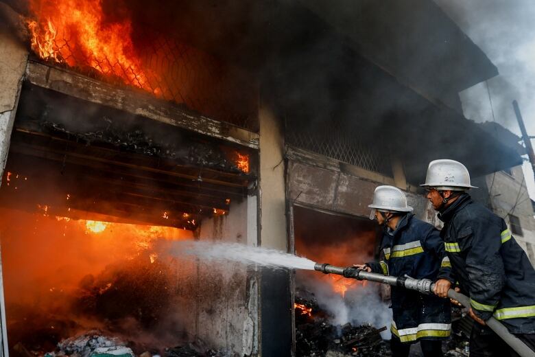 Fire crews in Gaza use a hose to attempt to put out a massive blase.