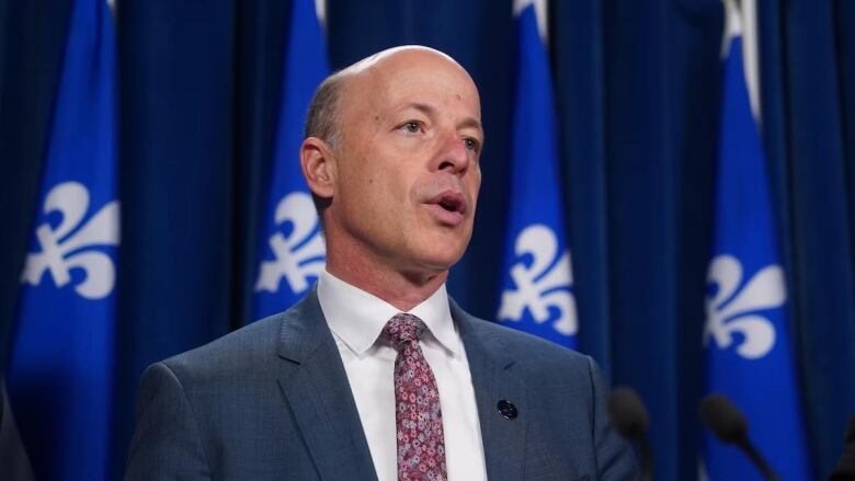 Man standing in front of Quebec flags 