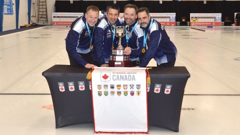 A curling team poses with its trophy 