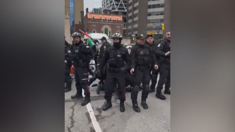 A bunch of police officers crowd a person and arrest them.