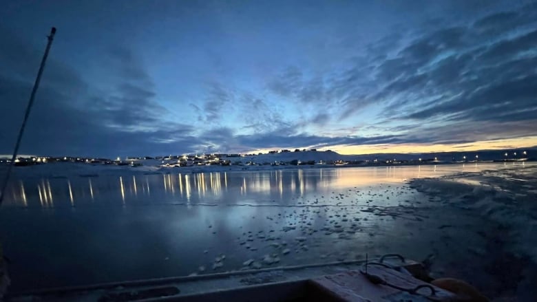 Open water by a snowy community.