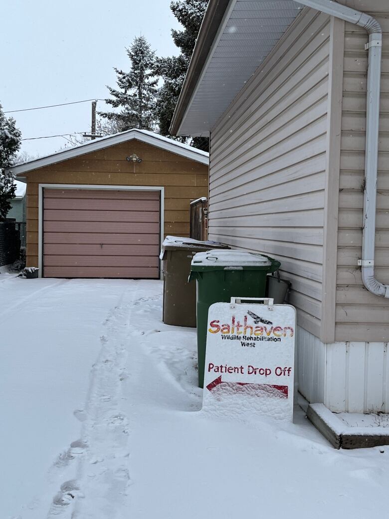 A white sign that points to the patient drop off at Salthaven West is covered in a fresh blanket of snow. 