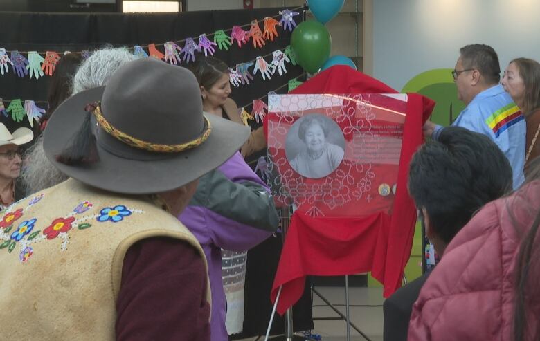 People squeeze in to view a plaque honouring Theresa Wildcat. 