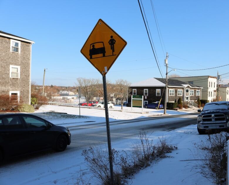 A snowy residential street with a sign reminding motorists to share the road 