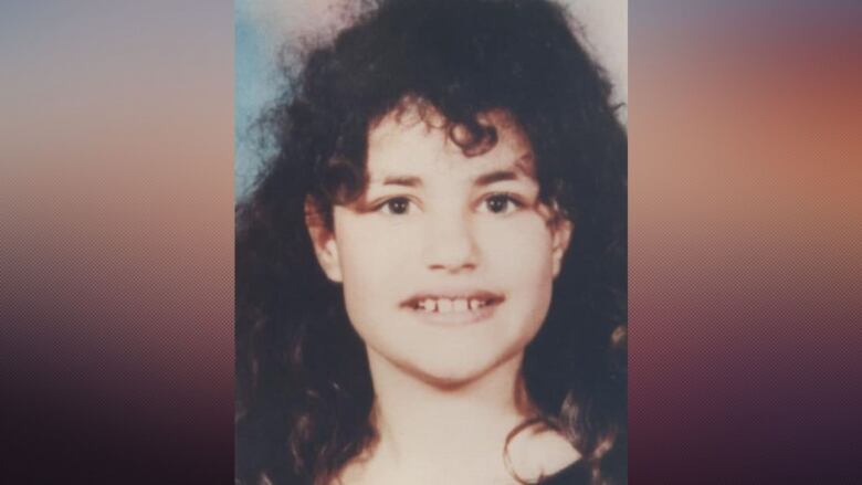 An image of a girl, with shoulder-length curly brown hair, shown from the shoulders up.