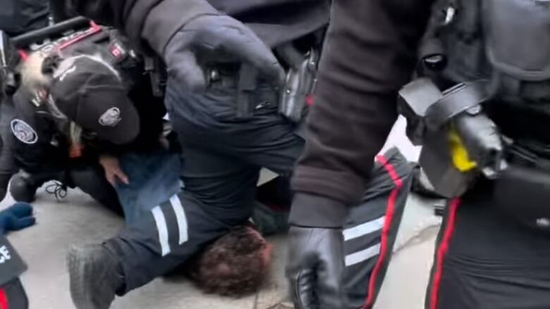 A police officer kneeling on a man's head and neck area during a protest.