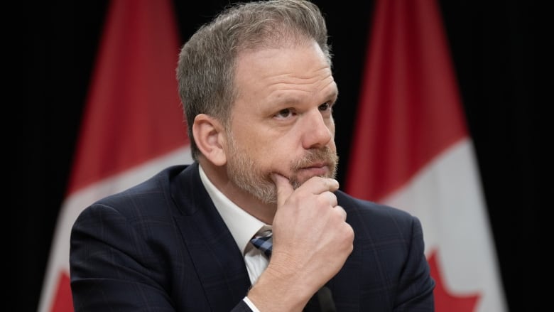 Health Minister Mark Holland listens to a question from a reporter during a news conference.