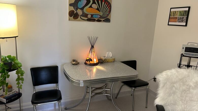 Two chairs and a table sit against a wall in a room.