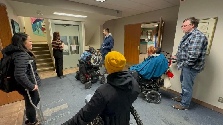 A group of people, some in wheelchairs, wait in a building lobby.