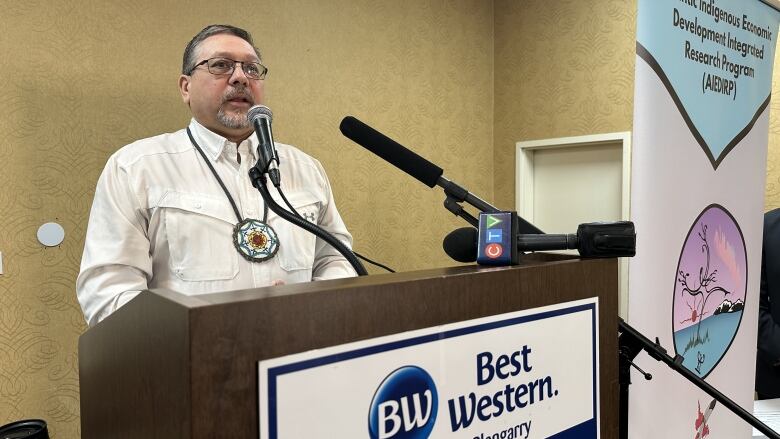 A man wearing a white shirt stands at a podium giving a speech in a conference room in Truro, Nova Scotia.