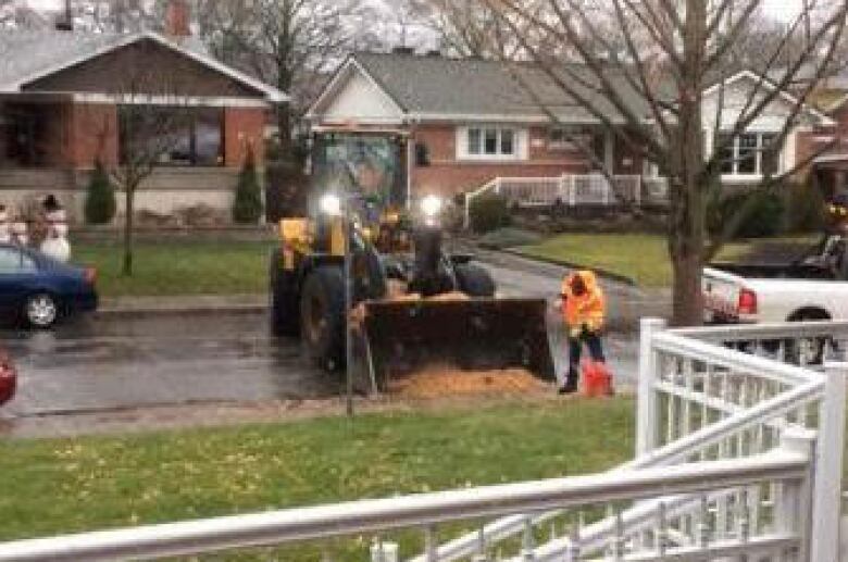 A front-end loader is positioned to have fruit swept into its charger.