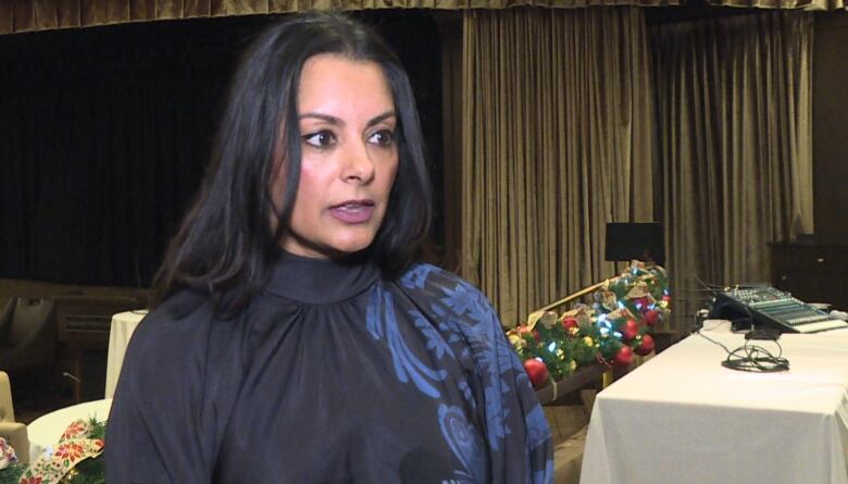 a woman with dark hair speaks to reporters