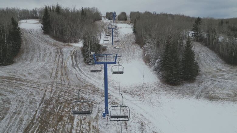 A nearly-dry ski hill in Saskatchewan with empty gondolas.