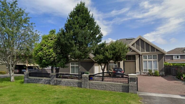 An image taken from Google Street View shows a beige suburban home with a green lawn below a clear blue sky.