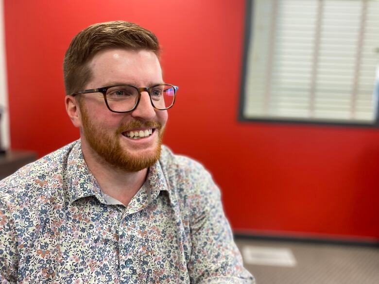 A man sits in an office and smiles