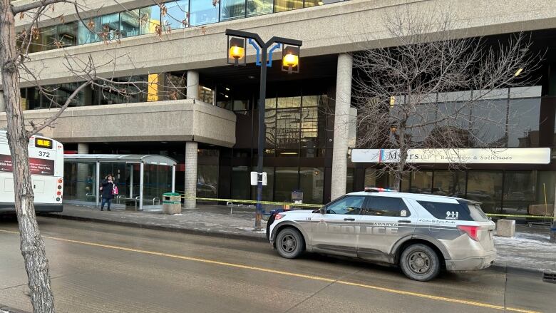 A police SUV is parked on a street behind a transit bus.