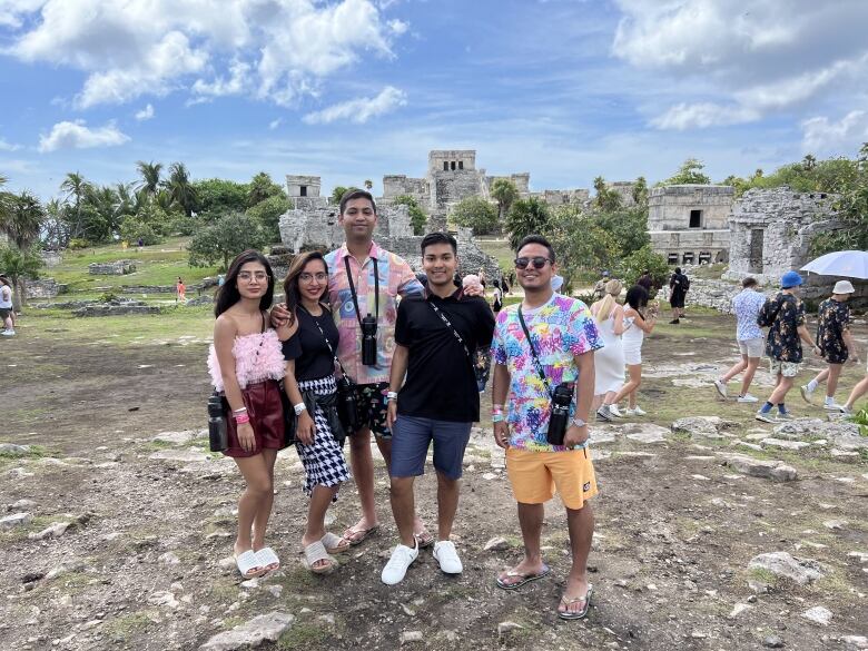 Five adults in a vacation photo in a hot country with ruins.