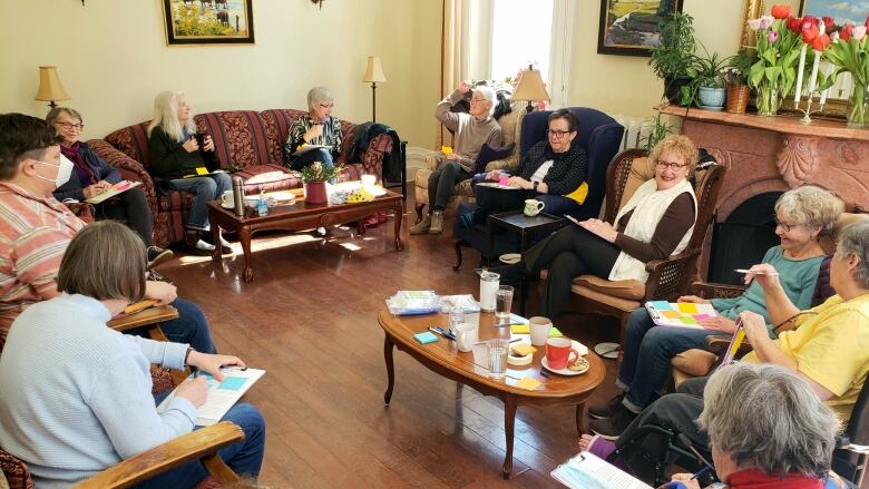 A group of older women gathered together in a living room.