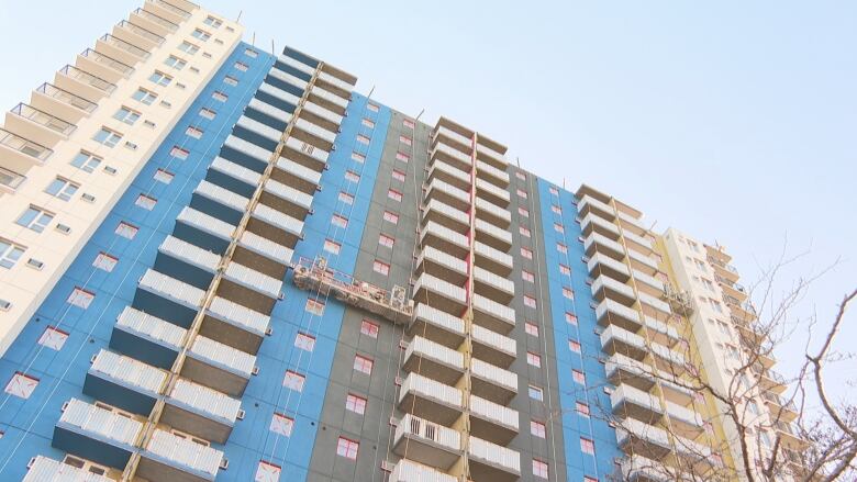 Side of building with workers on a platform on the side