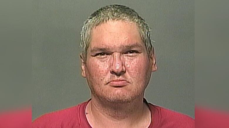 A mugshot of a man in a red shirt.