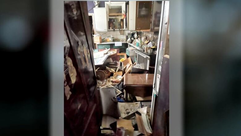 A picture of a kitchen with many object thrown around and drawers opened.