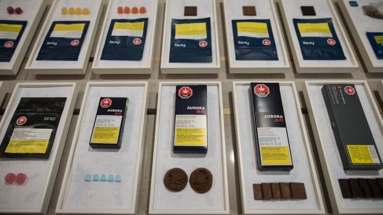 Packages of cannabis edibles are displayed on a table, in dark blue packaging.