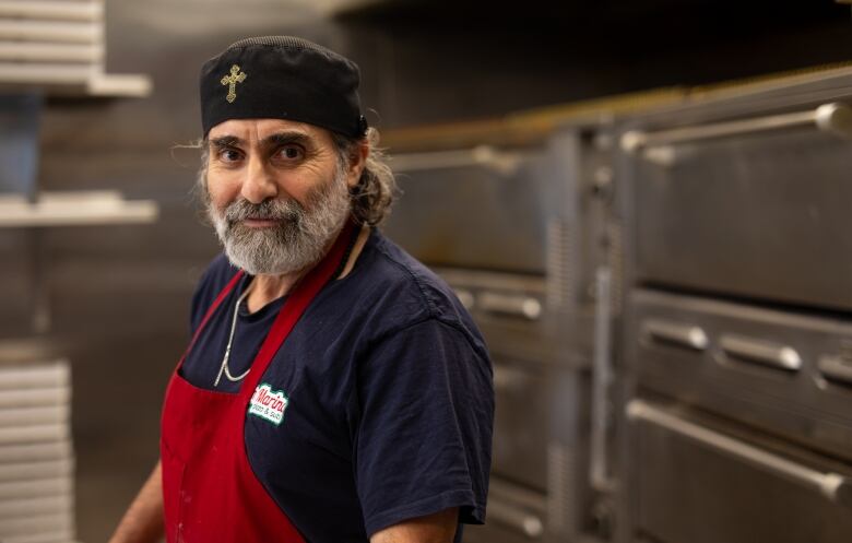 A pizza shop owner poses in his restaurant.