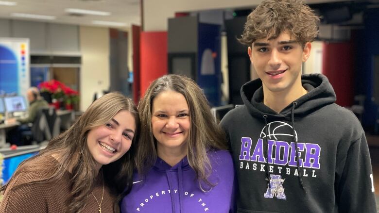 A teacher wearing a purple hoodie is flanked by two of her students in the CBC Windsor studio