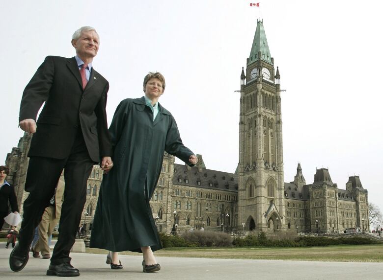 John Godfrey and his wife Patricia Bongard walk hand-in-hand in front of the Canadian Parliament in 2006.