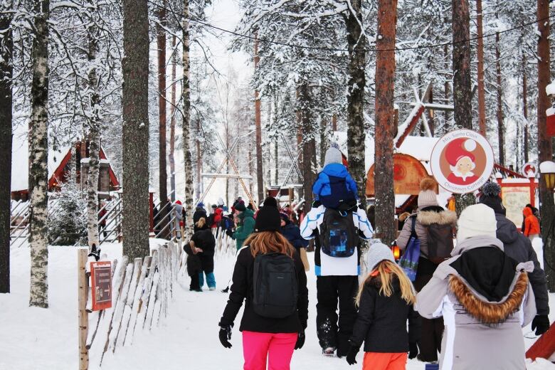 Groups of people in winter gear walk down a snowy path.