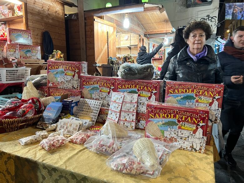 Board games in boxes arranged on a table. Two women walking past.