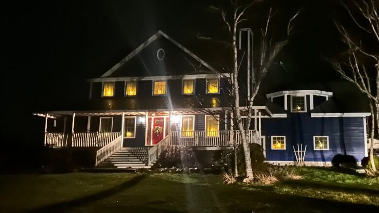 A large home with holiday decorations and plastic candles glowing in the windows.