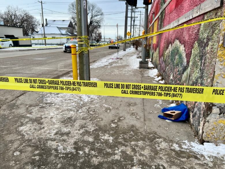 A street is seen taped off by police, with cruisers in the background.